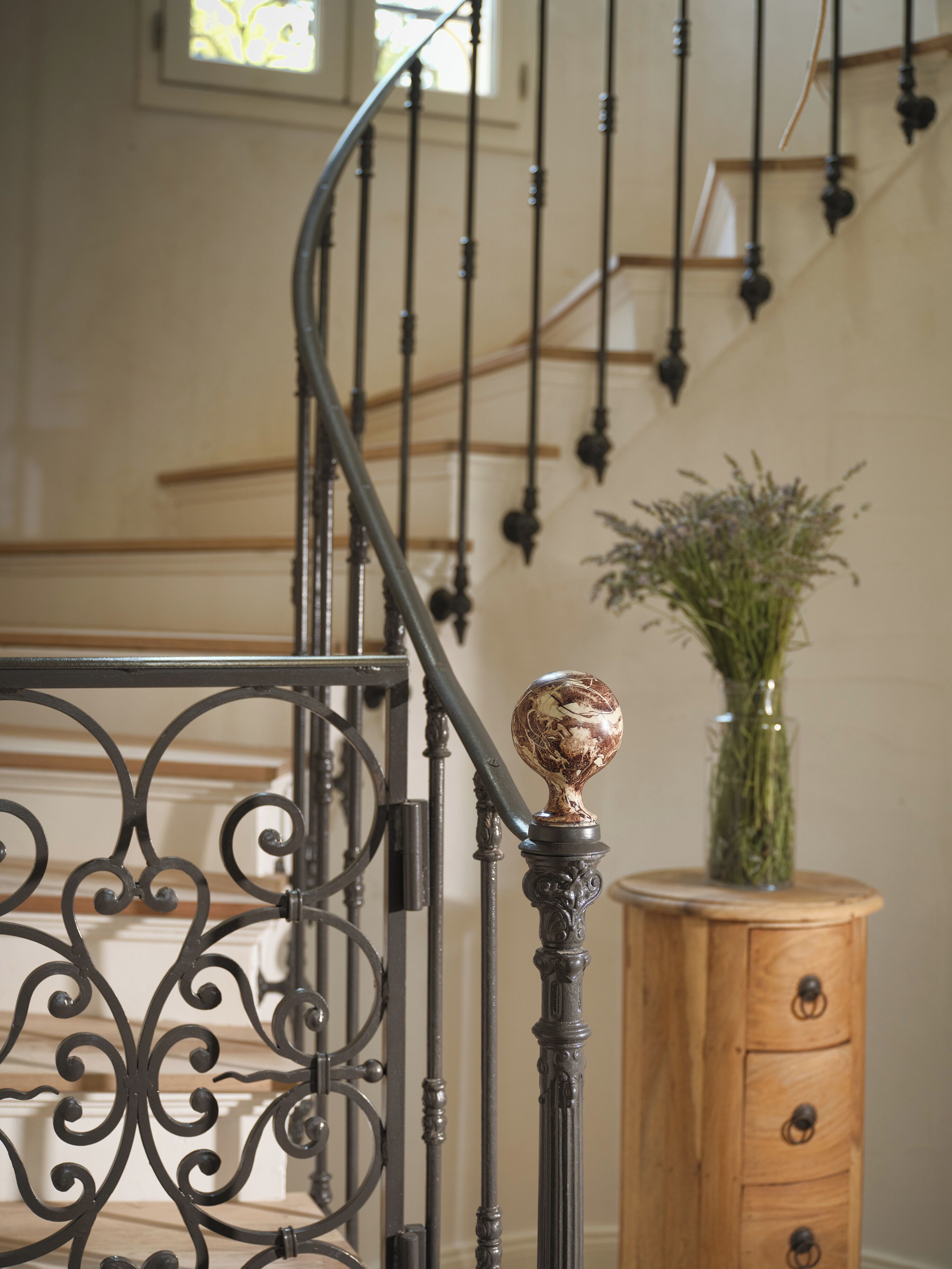 A staircase with ornate metal railings and a wooden cabinet with drawers.