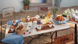 Ένα τραπέζι στρωμένο για πρωινό, με καρέκλες και ένα άτομο που στέκεται δίπλα σε μια πόρτα.