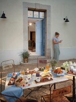 Una mesa con sillas y una persona de pie cerca de una puerta, lista para el desayuno.