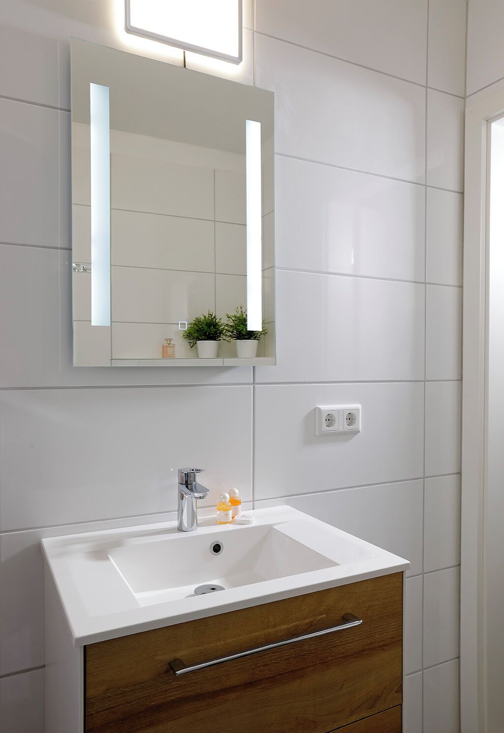 A bathroom with a white sink, a mirror, and a wooden cabinet.