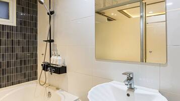 A bathroom with a bathtub, a sink, and a mirror.