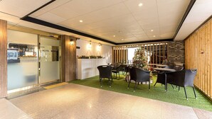 A hotel lobby with a reception desk, wicker chairs, a Christmas tree, and a green artificial turf area. - MARU HOTEL (Seoul)