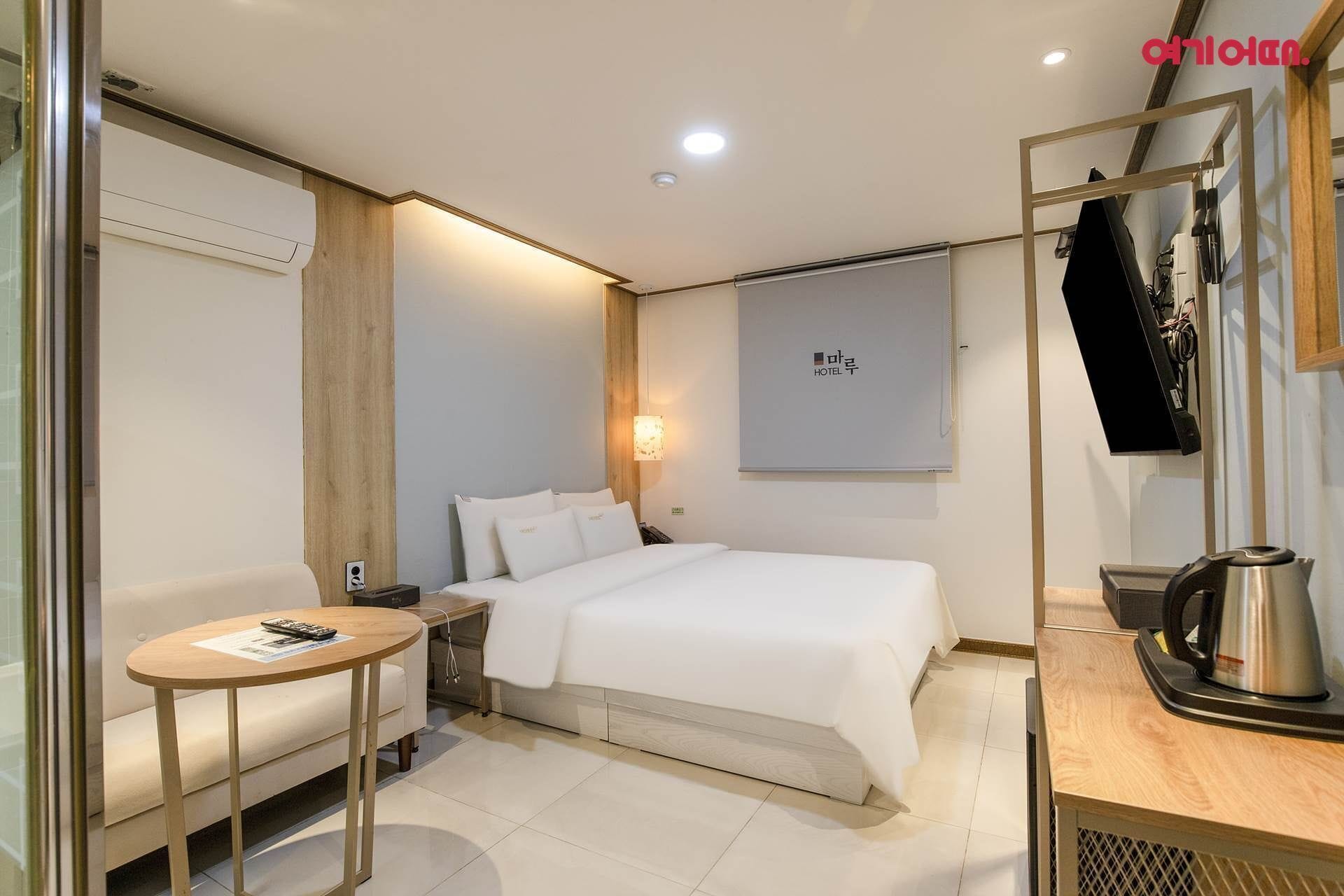 Een hotelkamer met een bed, een tafeltje, een stoel, een televisie en een koffiezetapparaat.