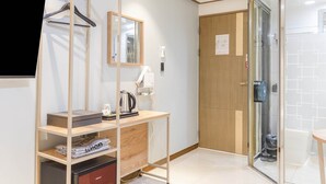 A modern bathroom with a wooden vanity, a mirror, a kettle, and a glass shower enclosure. - MARU HOTEL (Seoul)