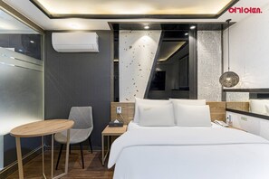 A modern hotel room with a bed, bedside table, chair, and an air conditioning unit. - MARU HOTEL (Seoul)