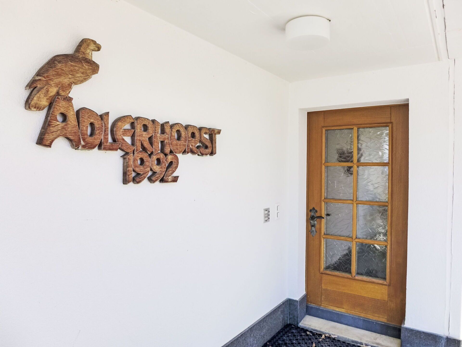 Une porte en bois avec un panneau en verre dépoli et un décor en métal représentant un aigle au-dessus.