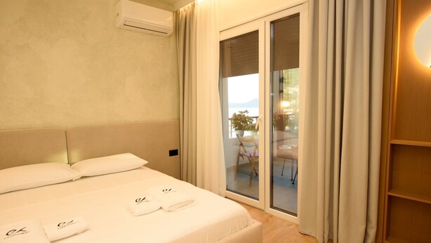 A hotel room with a bed, a sliding glass door to a balcony, and an air conditioning unit on the wall. - E&K Apartment 02 , Sea view, Free Parking (Vlora)