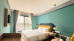 A hotel room with a bed, bedside table, chair, and a small table with a tray.