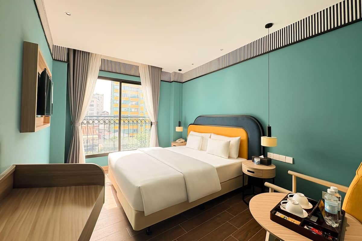 Ein Hotelzimmer mit Bett, Nachttisch, Stuhl und einem kleinen Tisch mit Tablett.