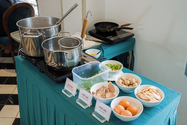 A buffet table with various food items and cooking utensils.