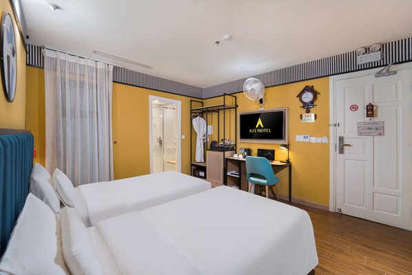 Une chambre d’hôtel avec deux lits, un bureau avec un ordinateur, une télévision, une horloge et une porte sur laquelle est indiqué le numéro de la chambre.