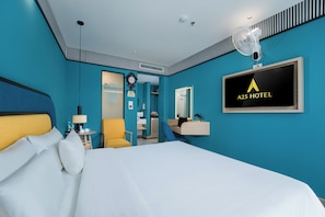 Une chambre d’hôtel comprenant un lit, un bureau, une chaise, un miroir, une horloge et une enseigne indiquant le nom de l’hôtel.