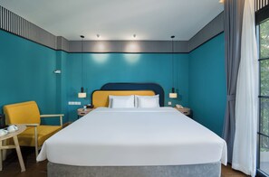 Habitación de hotel con una cama grande, una silla, mesitas de noche y vistas a través de la ventana.
