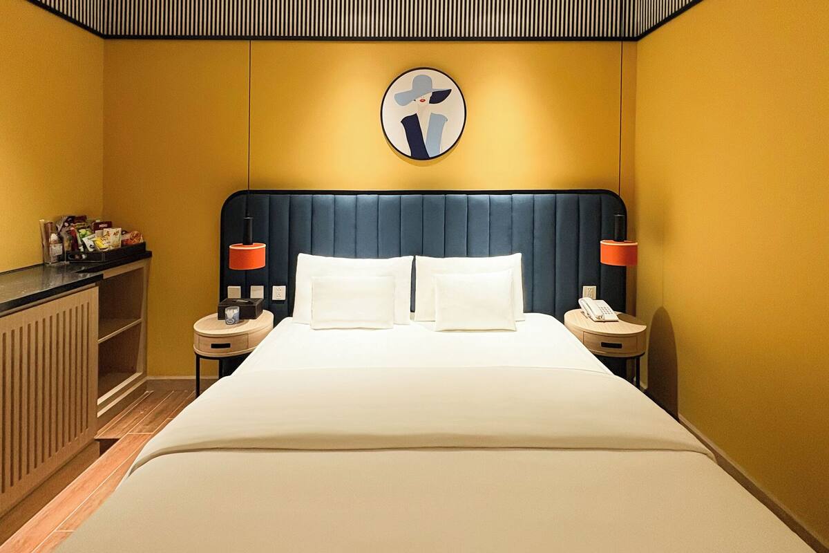 Ein Hotelzimmer mit einem großen Bett, zwei Nachttischen, einer runden Wanduhr und einem Holzschrank.