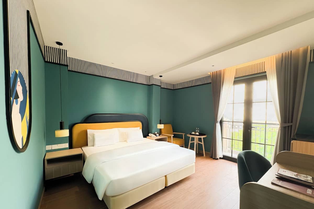 Ein Hotelzimmer mit einem großen Bett, Nachttischen, einem Schreibtisch und einem Stuhl.