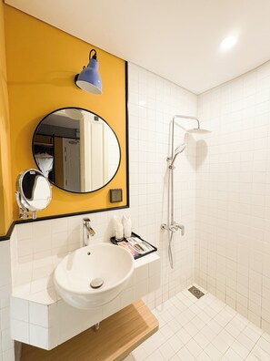 A bathroom with a white sink, a mirror, a blue wall-mounted lamp, and a shower. - A25 Premium Hotel - 130 Ba Trieu (Hanoi)