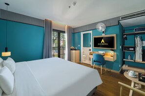 A hotel room with a bed, a desk, a TV, and a wardrobe.