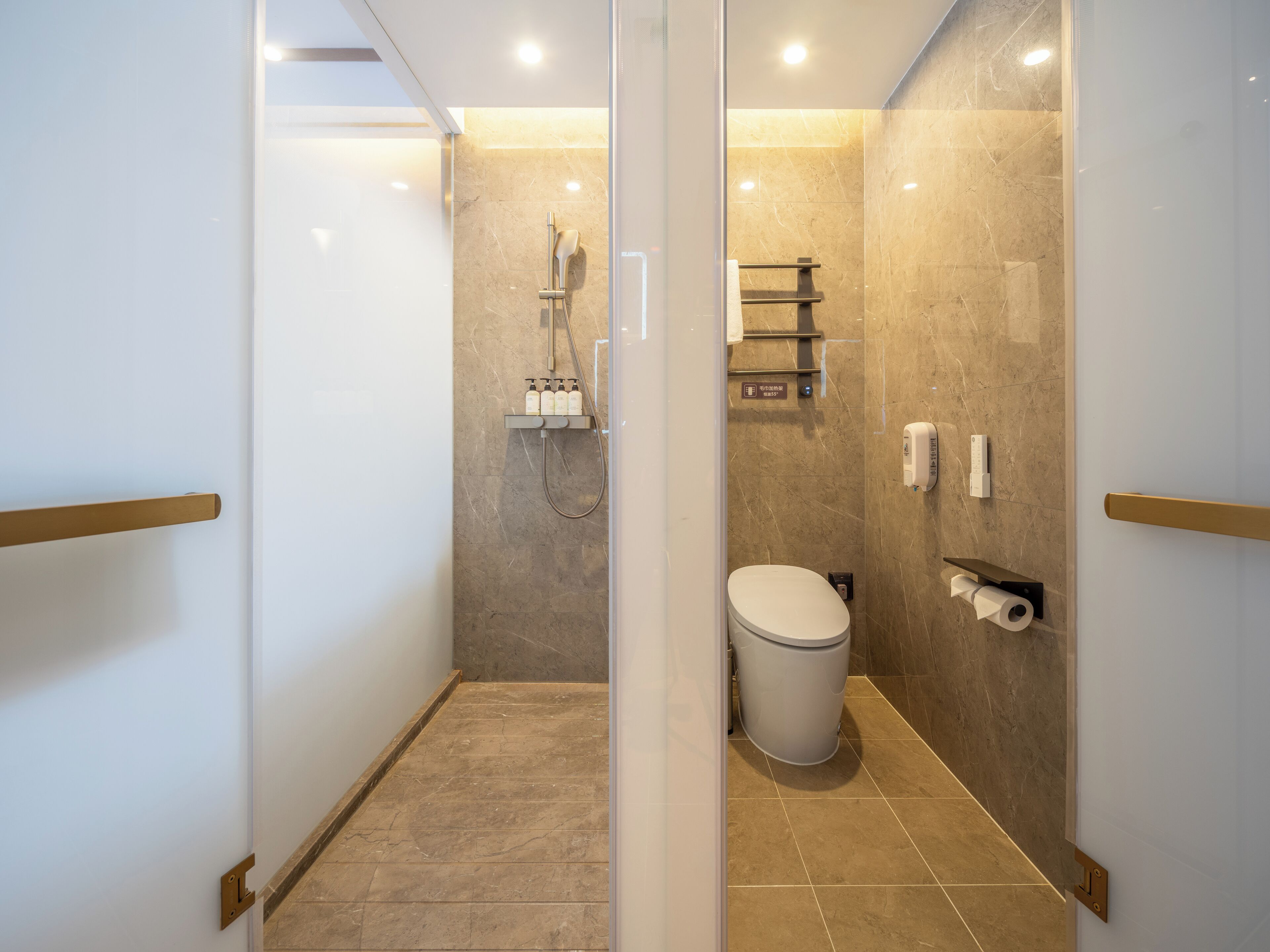 Un baño moderno con mampara de vidrio, zona de ducha, inodoro y perchero.