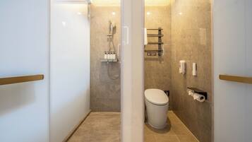 Un baño moderno con mampara de vidrio, zona de ducha, inodoro y perchero.