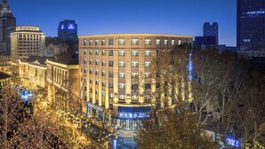 A multi-story hotel with a curved facade, illuminated windows, and a prominent entrance. - Nostalgia S Hotel(Tianjin Jinwan Plaza) (Tianjin)