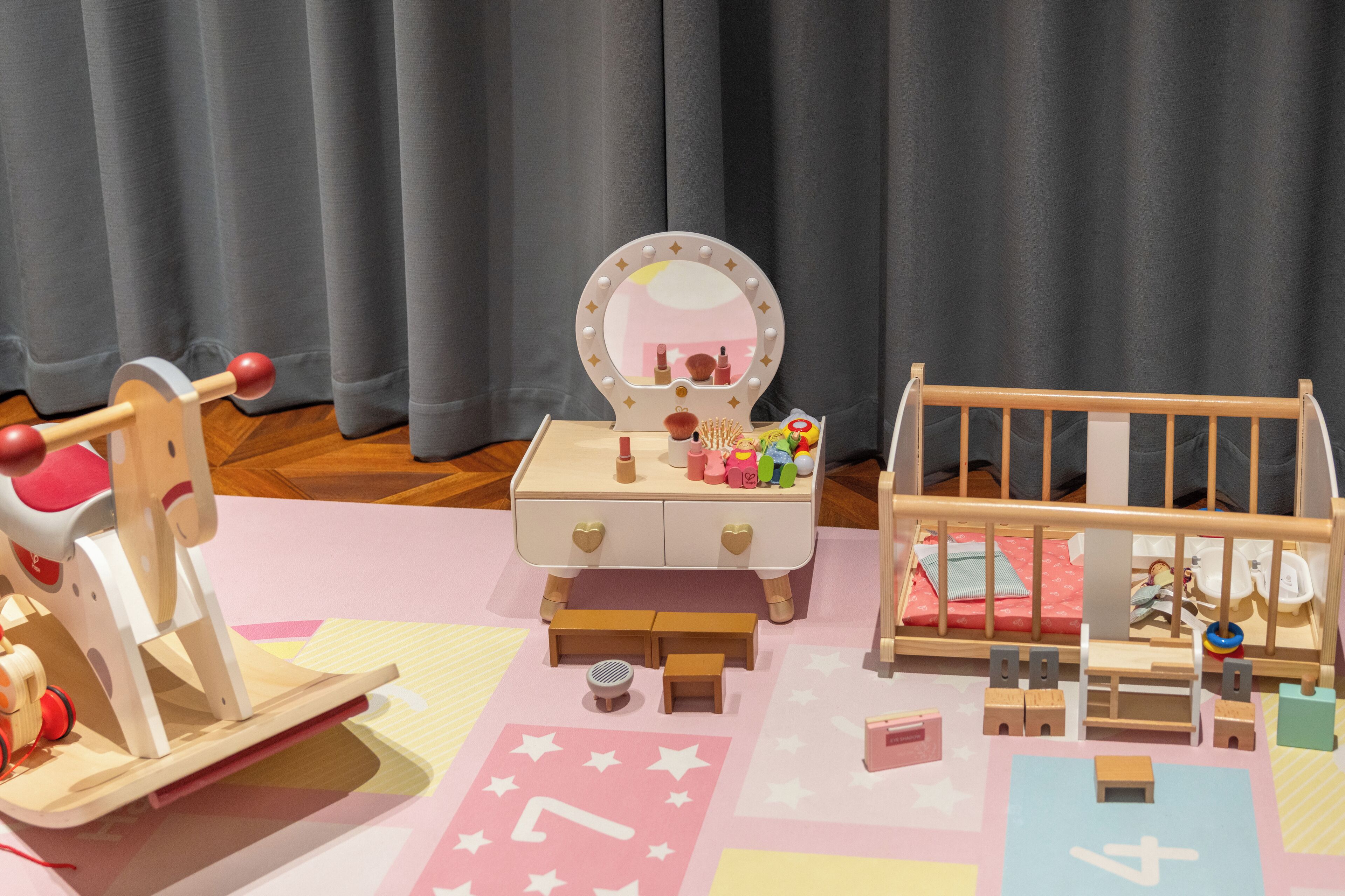 A dollhouse with a vanity table, a bed, and a small table with a mirror.