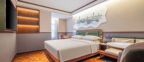 Habitación de hotel con una cama grande, una cama más pequeña, un televisor, un cuadro y piso de madera.