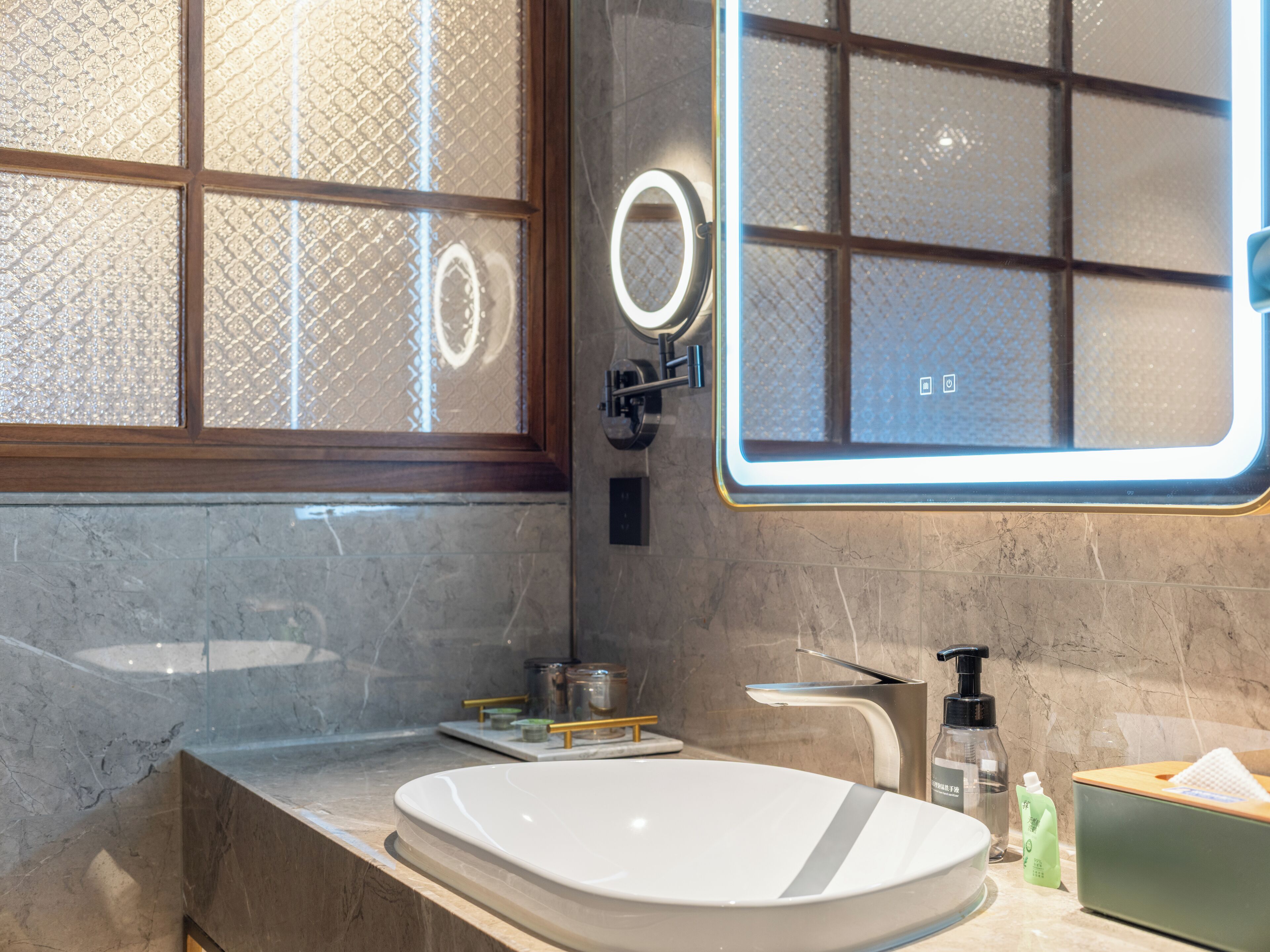 A modern bathroom with a large mirror, a sink, and a window with frosted glass.