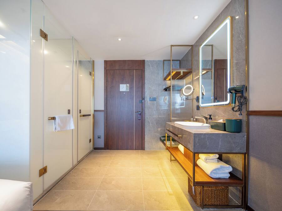 A modern bathroom with a glass shower enclosure, a wooden door, a vanity with a mirror, and a towel rack.