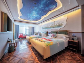 Habitación de hotel con techo estrellado, dos camas con ropa de cama colorida, una mesita y una mesita de noche.