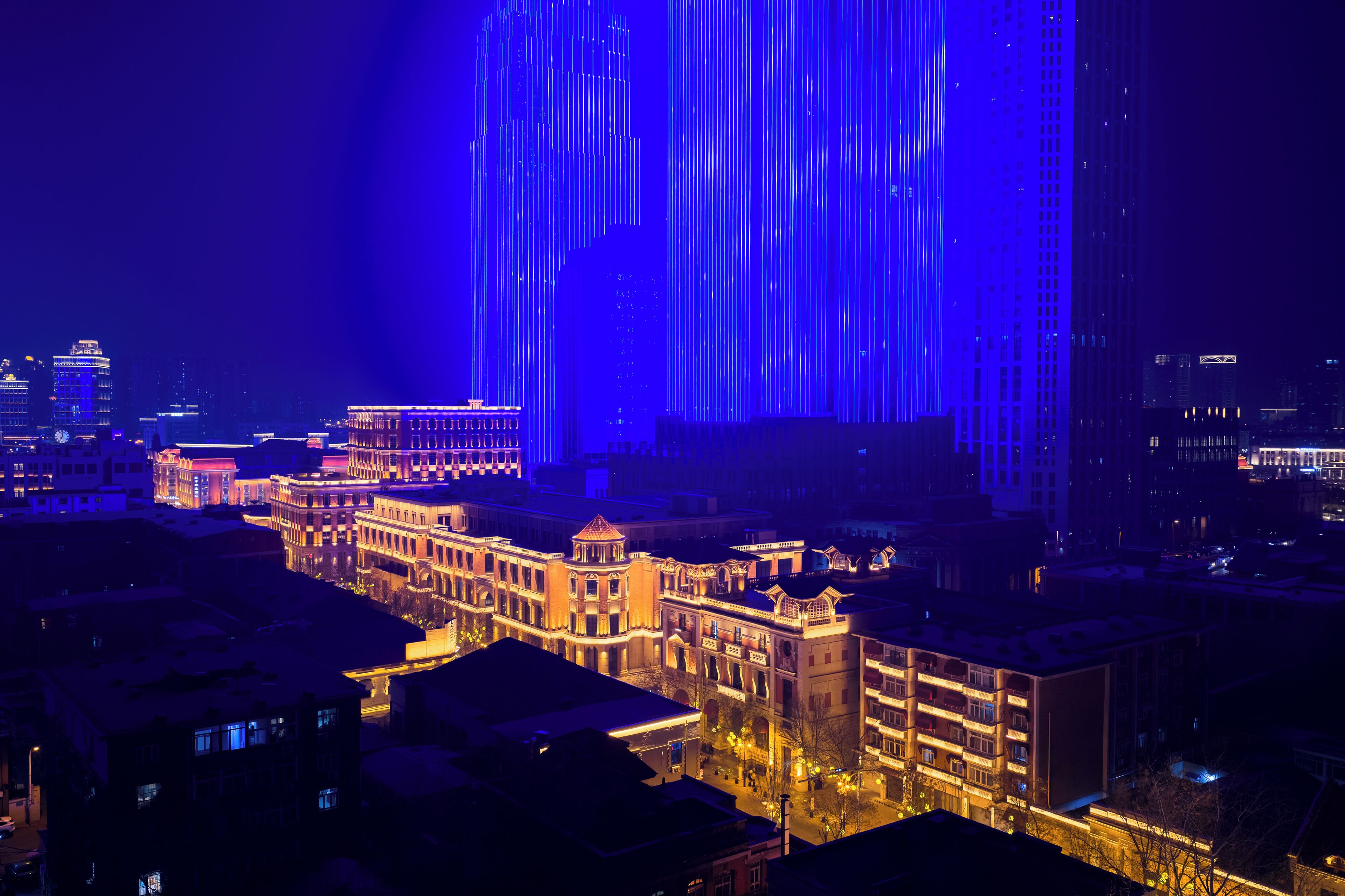 A cityscape at night with illuminated buildings and a prominent vertical light display.