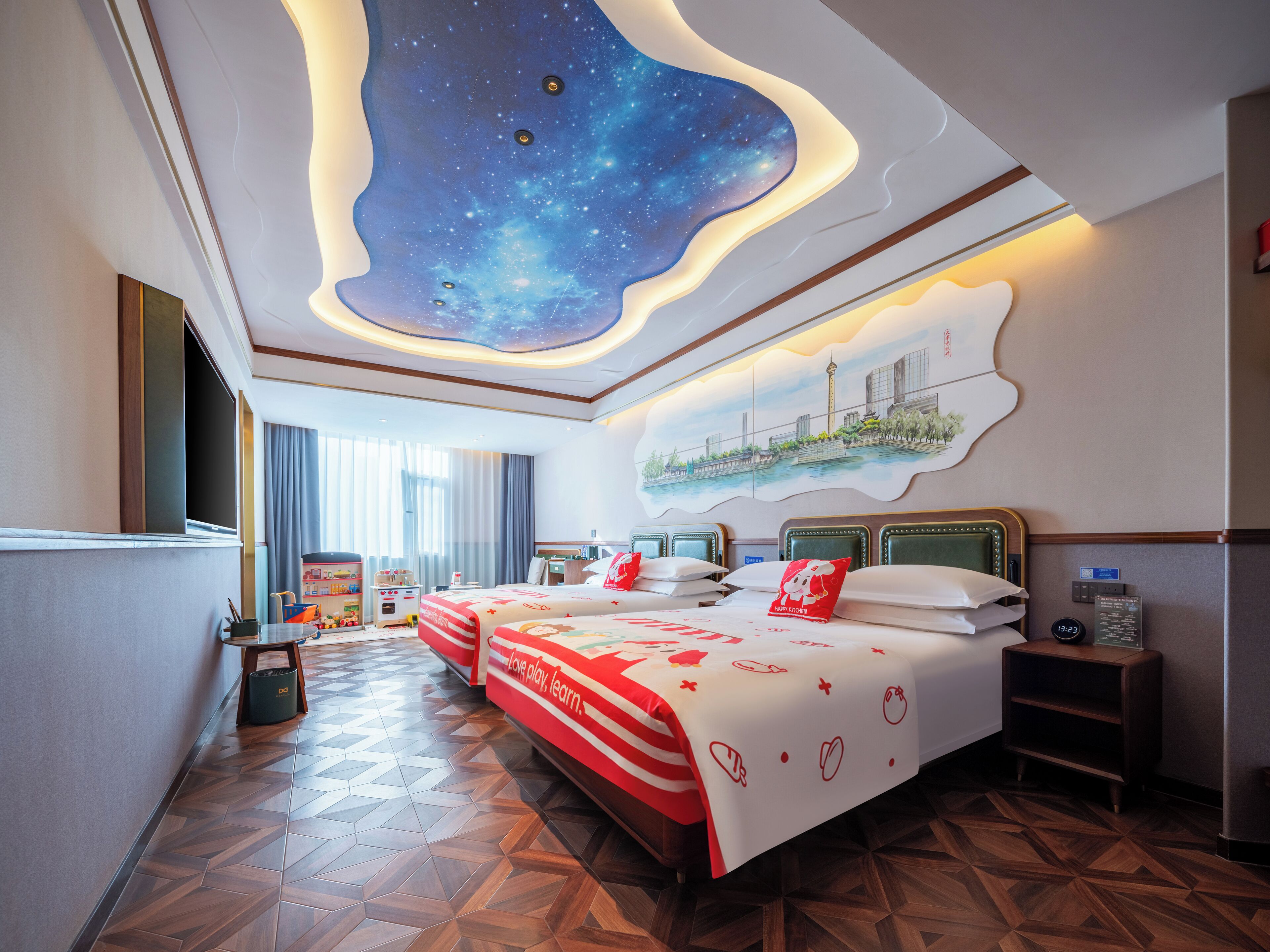 Ein Hotelzimmer mit Himmeldesign, das Sterne zeigt, ein Bett mit rot-weißer Bettdecke und ein Stadtbild an der Wand.