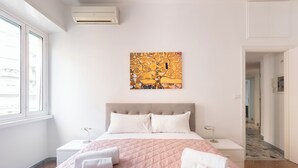 A hotel room with a bed, two bedside tables, a wall-mounted air conditioner, and a window. - Macedonia 30 Bright Flat (Rome)