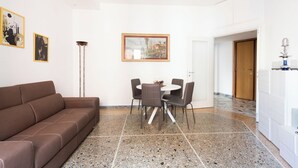 A modern living room with a brown sofa, a dining table with chairs, and artwork on the walls. - Macedonia 30 Bright Flat (Rome)