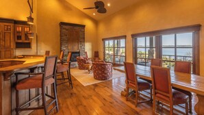 Una cocina amplia con chimenea de piedra, ventanas grandes con vistas y un comedor de madera con sillas.