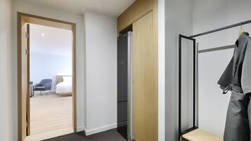 A modern hotel room with a wooden wardrobe, a black-framed mirror, and a grey carpet.