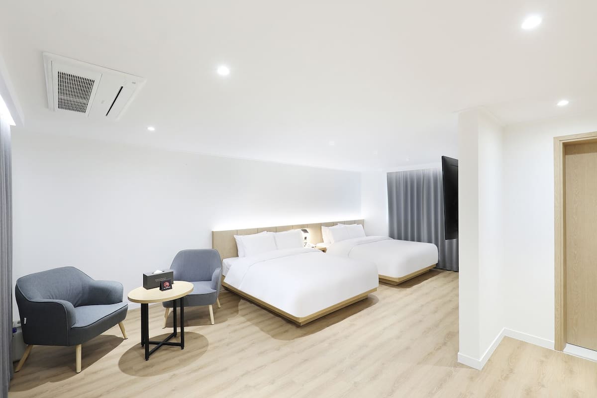 A modern hotel room with a large bed, a small desk, a chair, and a TV.