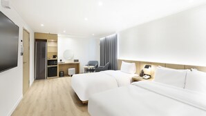 Moderni hotellihuone, jossa on kaksi sänkyä, työpöytä, tuoli, mikroaaltouuni, kahvinkeitin ja televisio.