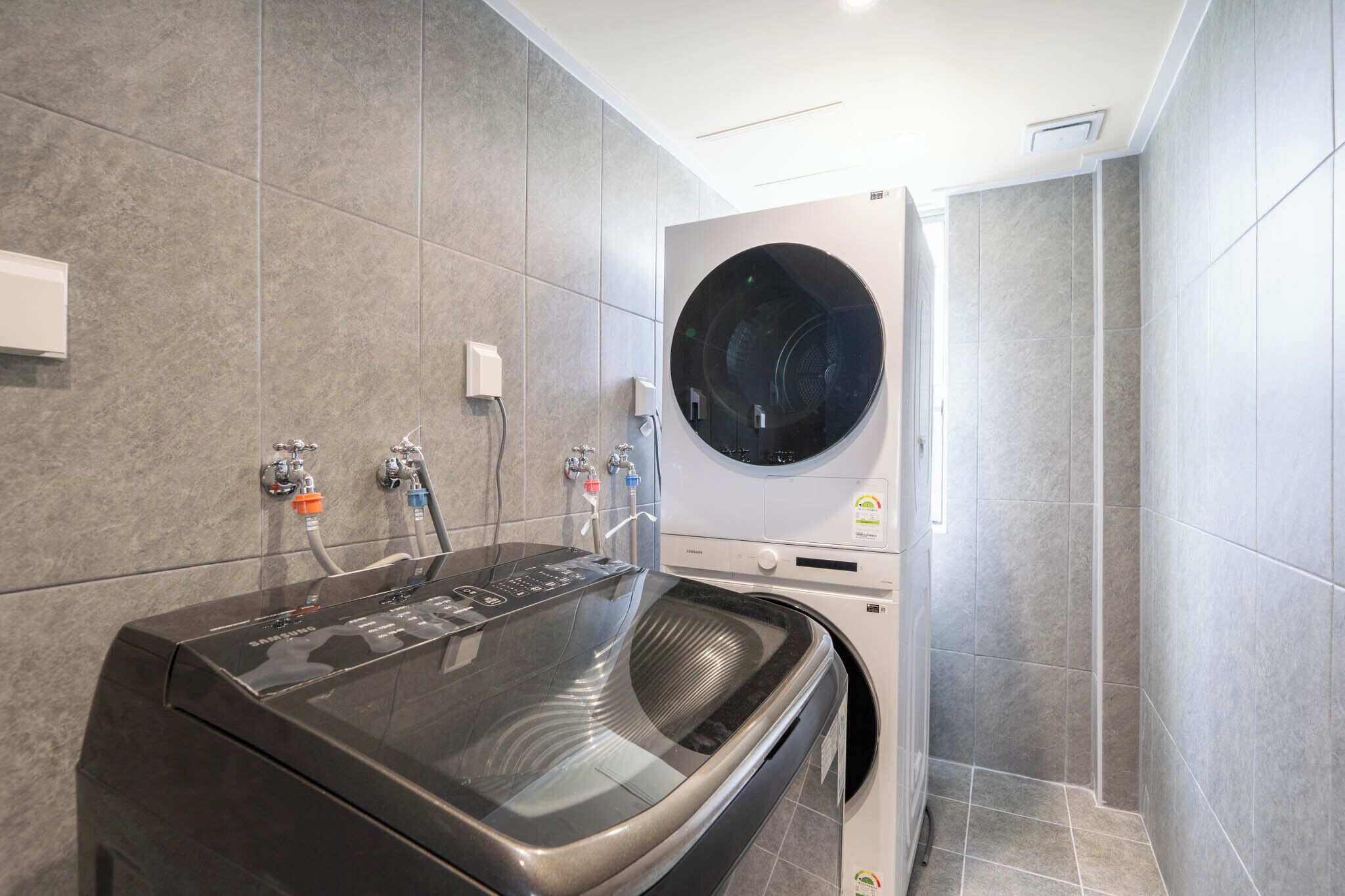 Une buanderie moderne équipée d’un lave-linge à chargement frontal et d’un sèche-linge encastré.