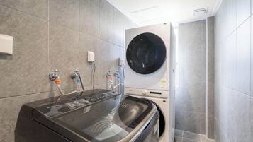 Une buanderie moderne équipée d’un lave-linge à chargement frontal et d’un sèche-linge encastré.