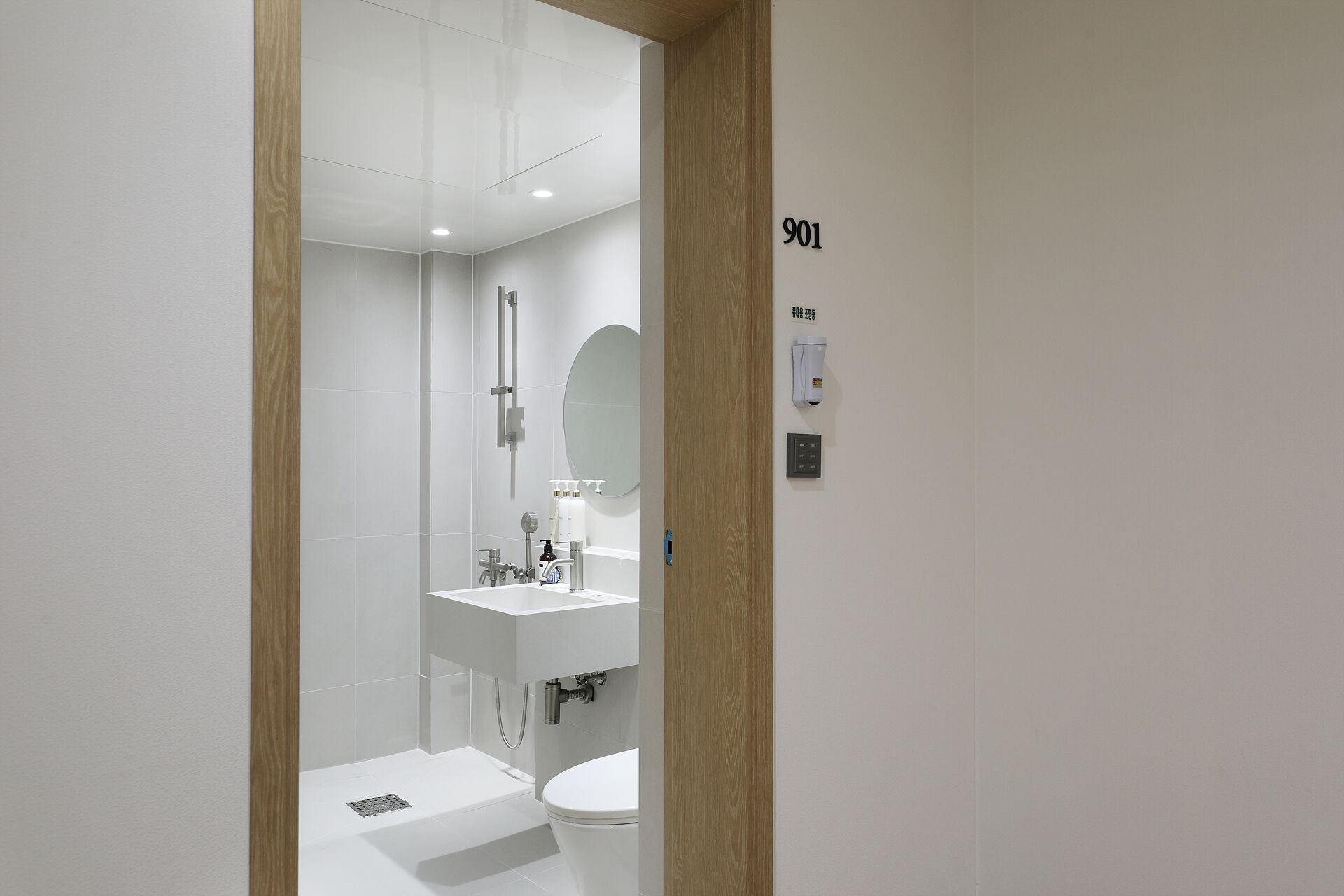 A modern bathroom with a white sink, mirror, and toilet.