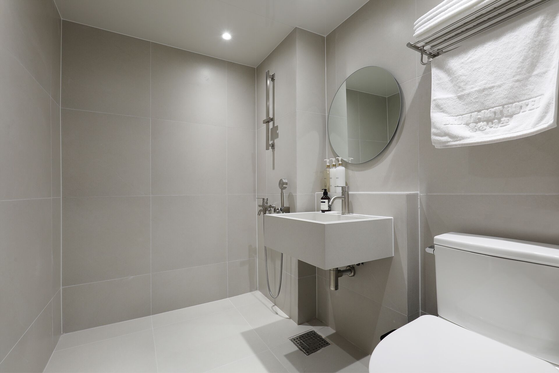 A modern bathroom with a shower, sink, toilet, and a towel rack.