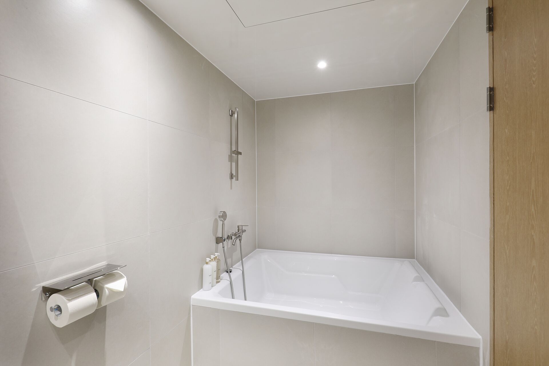 Ein modernes Badezimmer mit begehbarer Dusche, Toilettenpapierhalter und einer Badewanne.