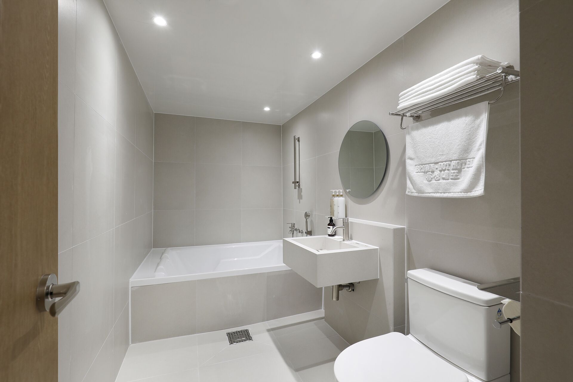 A modern bathroom with a bathtub, a sink, a toilet, and a mirror.