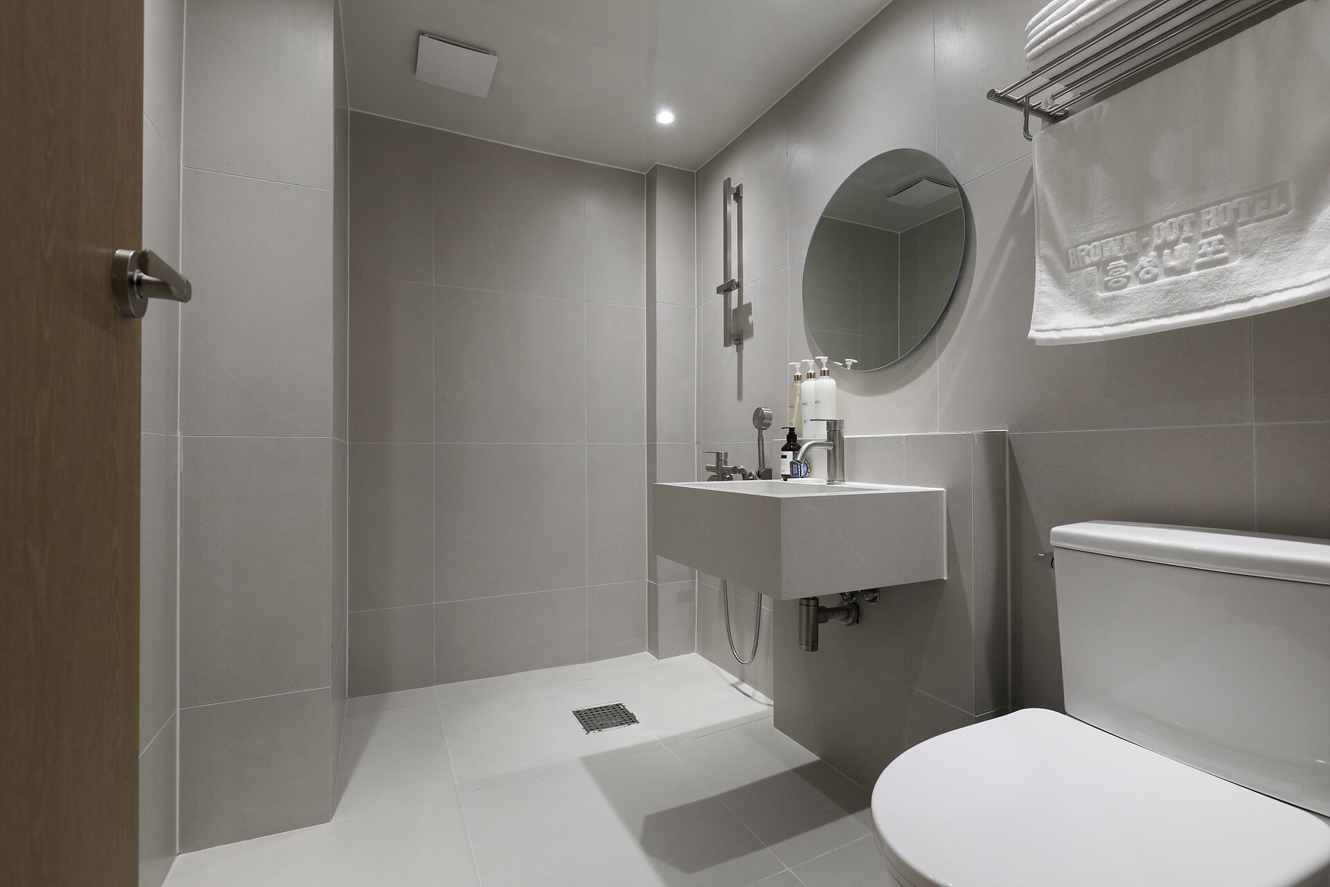 A modern bathroom with a shower, toilet, sink, and mirror.