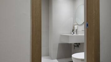 Une salle de bain moderne avec des toilettes, un lavabo et un miroir.
