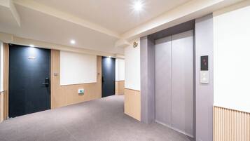 Un pasillo con dos ascensores, una puerta negra y un letrero que indica la habitación 8F.