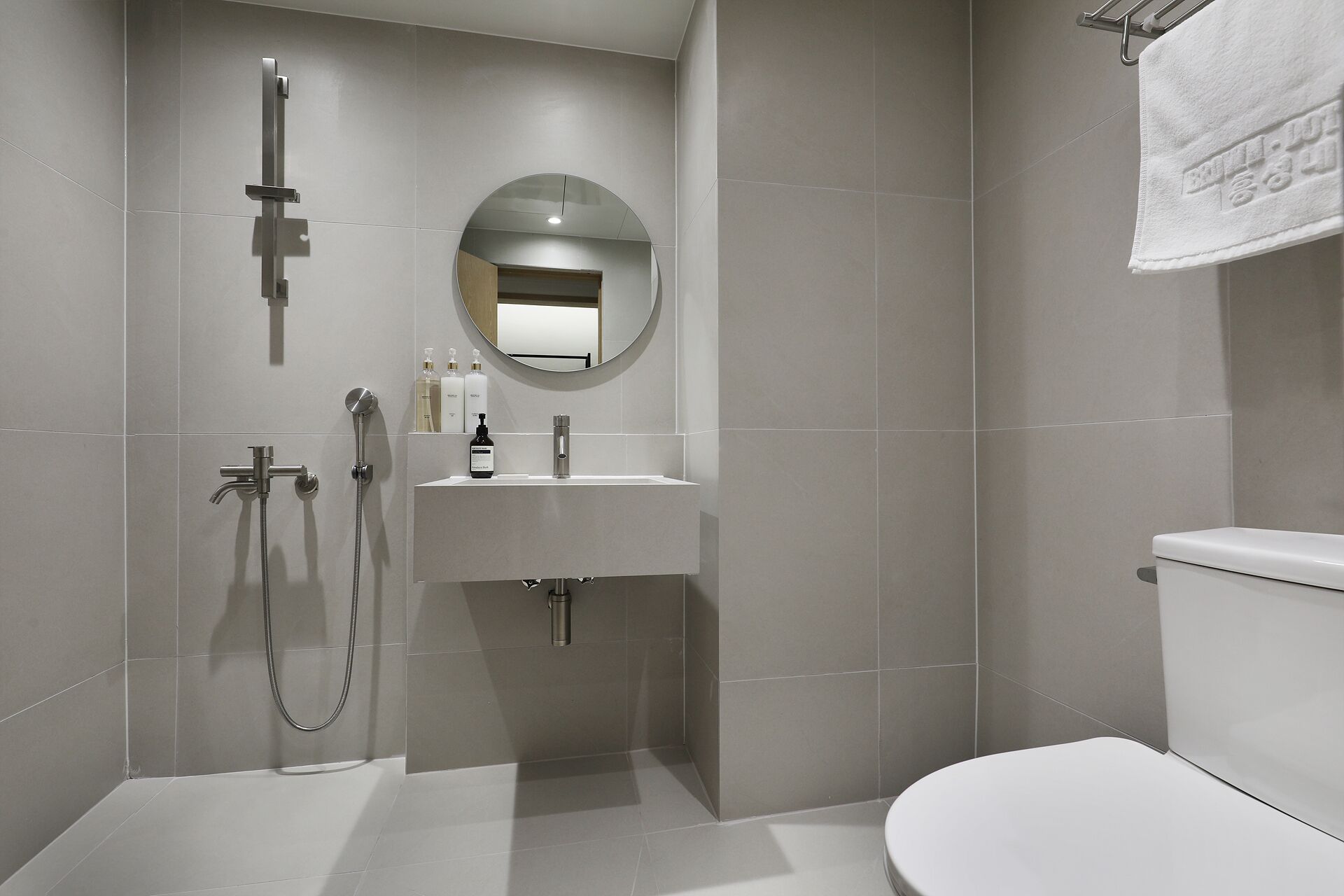 Un baño moderno con inodoro, lavamanos, espejo y ducha.