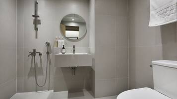 Un baño moderno con inodoro, lavamanos, espejo y ducha.