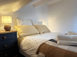 A neatly made bed with patterned bedding, a bedside lamp, and a blue nightstand with drawers.
