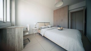 Un dormitorio moderno con cama, mesita de noche, silla y armario.